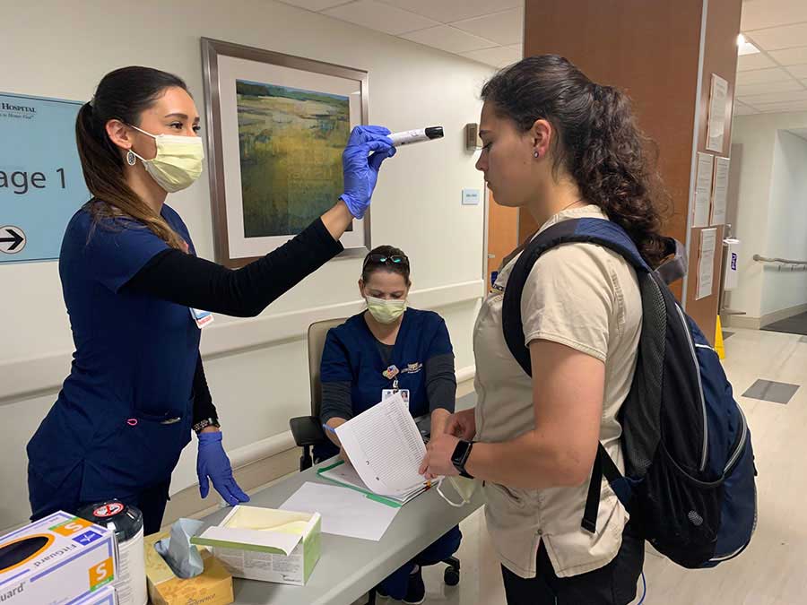 Pediatric nurse, Sarah Piepryzyca, takes an employee’s temperature at one of the facility’s entrances.