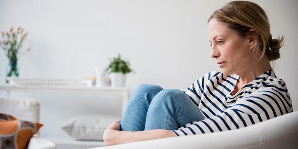 woman sitting alone on couch looking off
