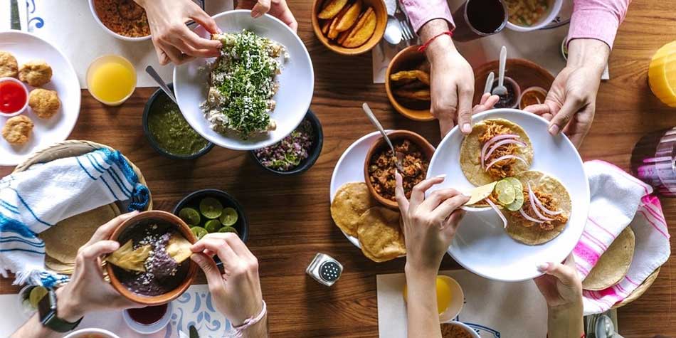 Hands reach for tacos across a table.