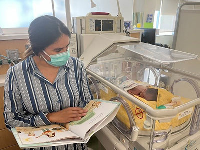 Mother reading book to baby in NICU
