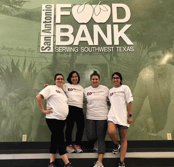 volunteers posing under a San Antonio food bank sign
