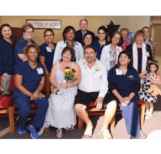 hospital staff posing with a bride and groom at their wedding in the hospital chapel