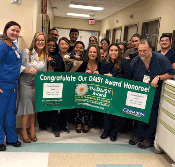 staff holding a banner that says Congratulate Our DAISY Award Honoree