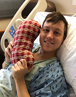 Mason Bettes in his hospital bed smiling with a Kidney pillow