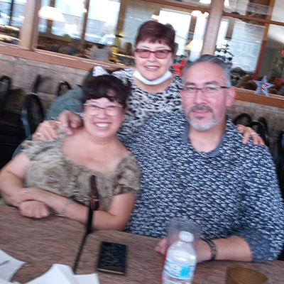 Adrian with his wife and family member at a restaurant